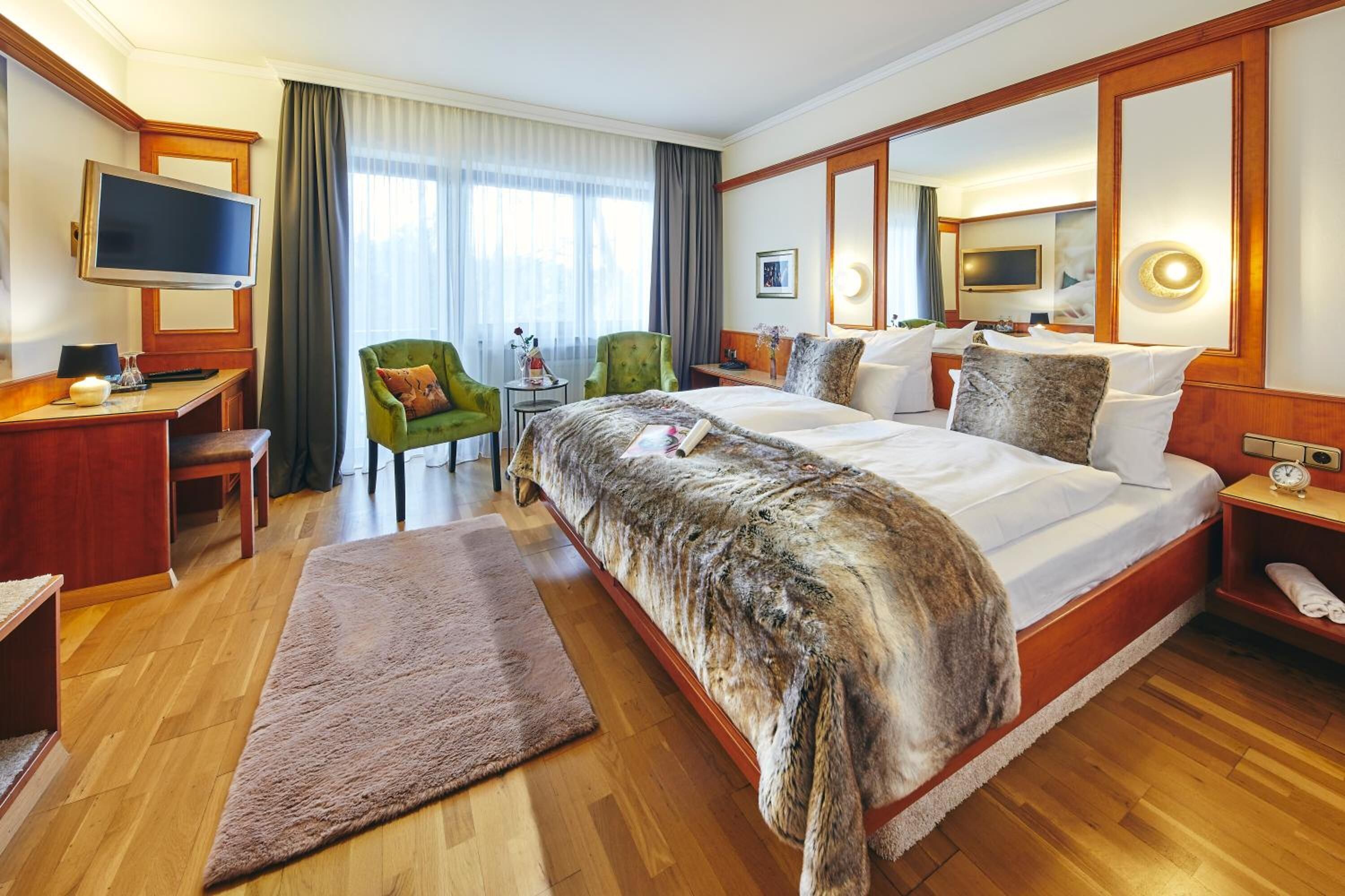 A hotel room with a large bed, a desk, a television, and a chair.