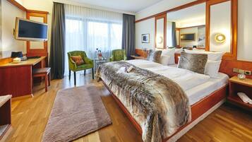 A hotel room with a large bed, a desk, a television, and a chair.