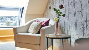 Un salon moderne avec un canapé, une petite table ronde et un vase rempli de fleurs.