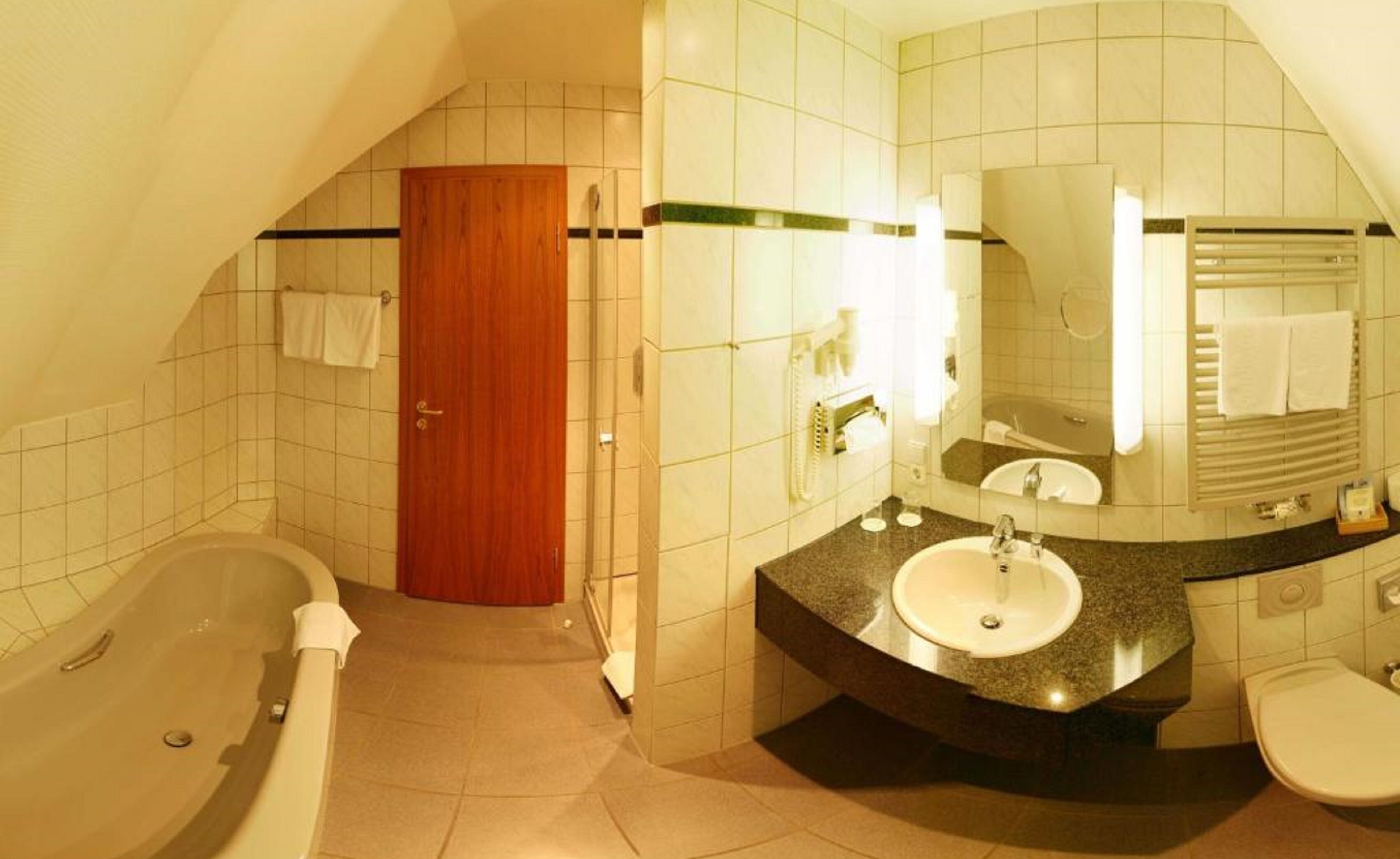 A bathroom with a bathtub, a sink, and a toilet. There is a wooden door and a mirror above the sink.