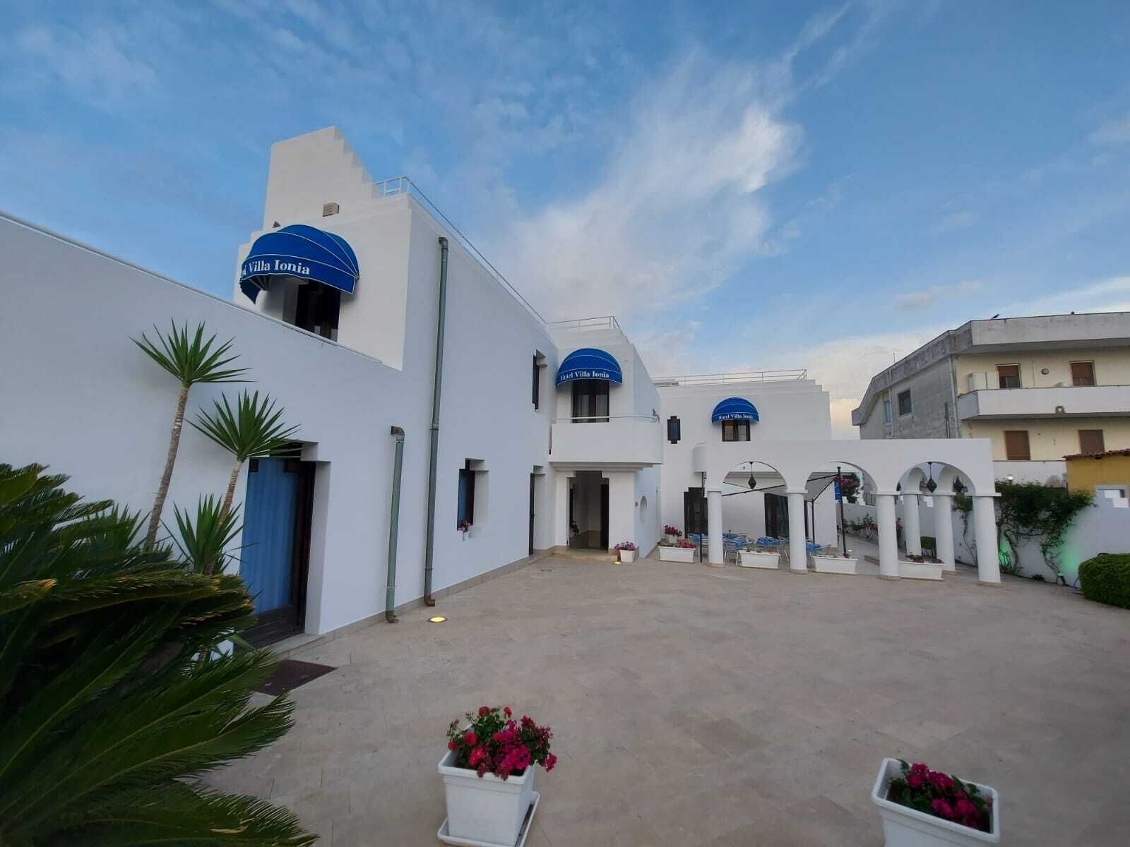 A courtyard with white buildings, blue domed roofs, and potted plants.
