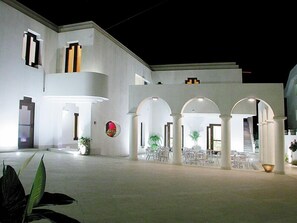 A modern building with a courtyard, featuring white walls, multiple arches, and a staircase leading to an upper level. - Hotel Villa Ionia (Avola)