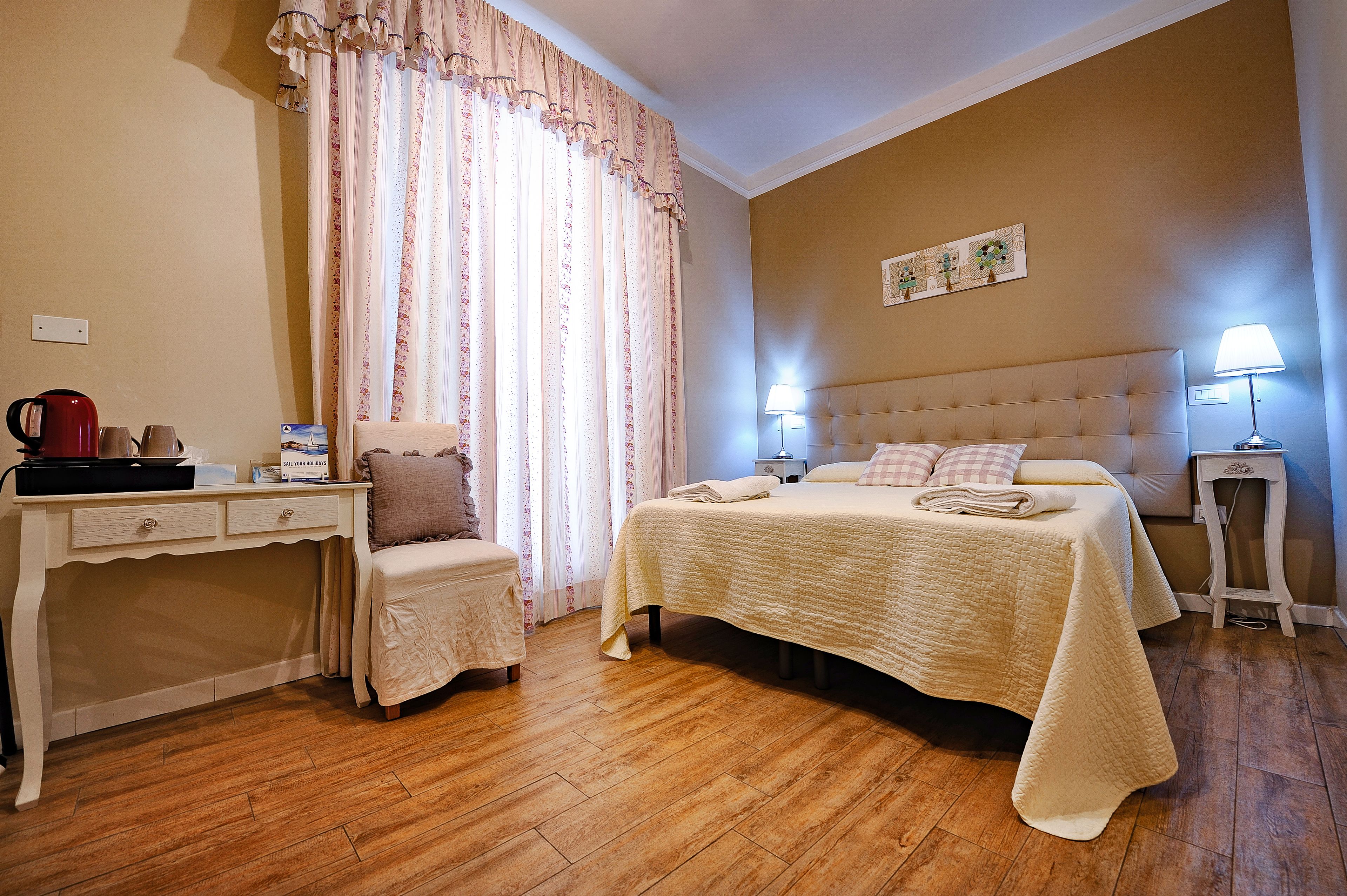 A neatly arranged bedroom with a bed, bedside tables, a desk, and a chair.