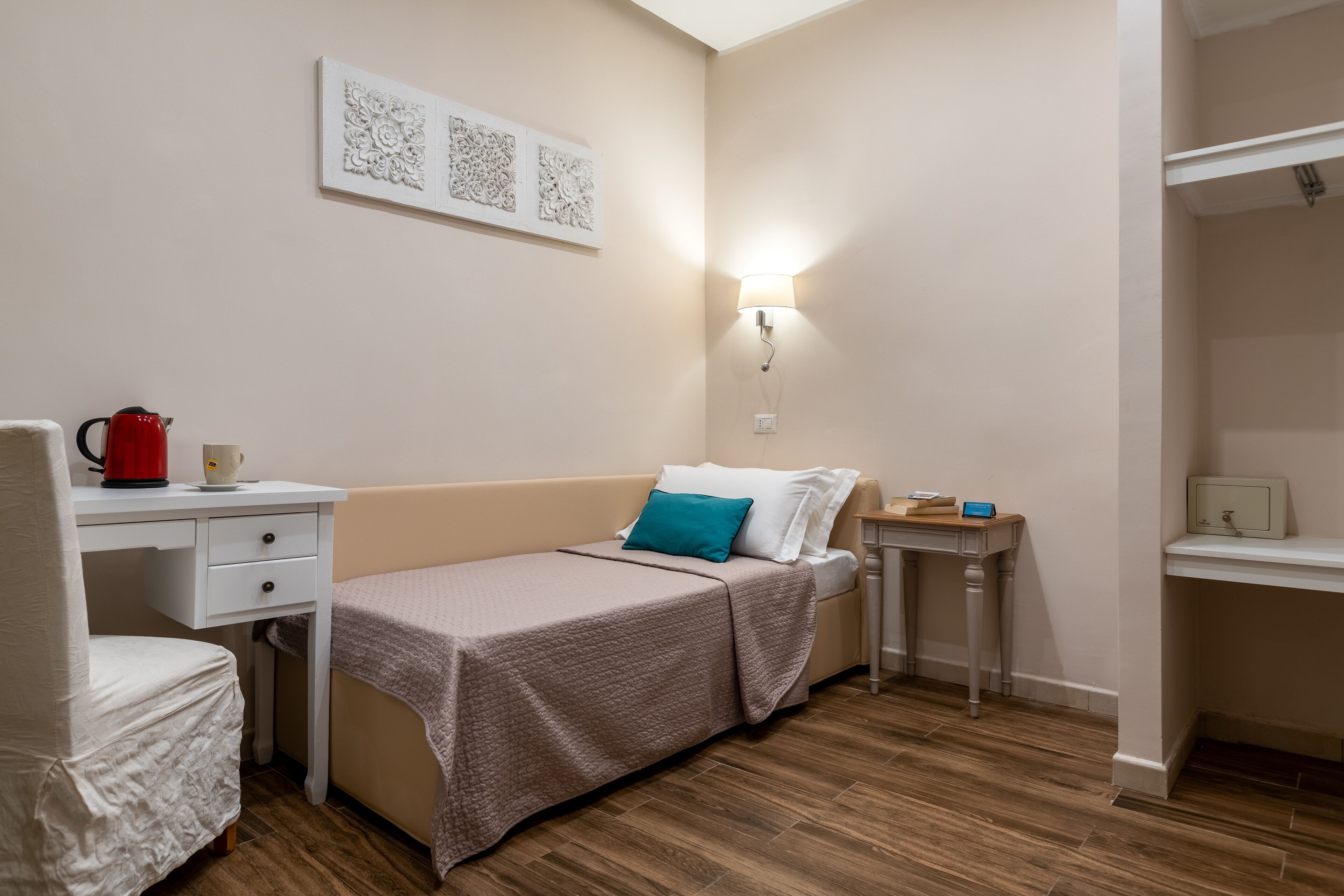 A small, neatly arranged bedroom with a single bed, a desk, and a chair.