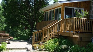 Une terrasse en bois avec un escalier menant à un porche abrité.
