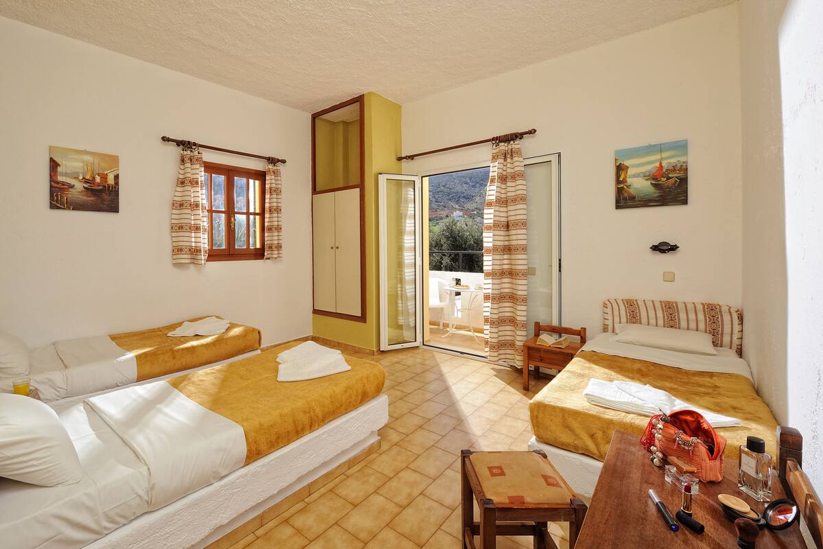 A hotel room with two beds, a balcony, and a table with toiletries.