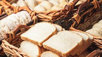 Wicker baskets filled with bread and eggs on a wooden surface.