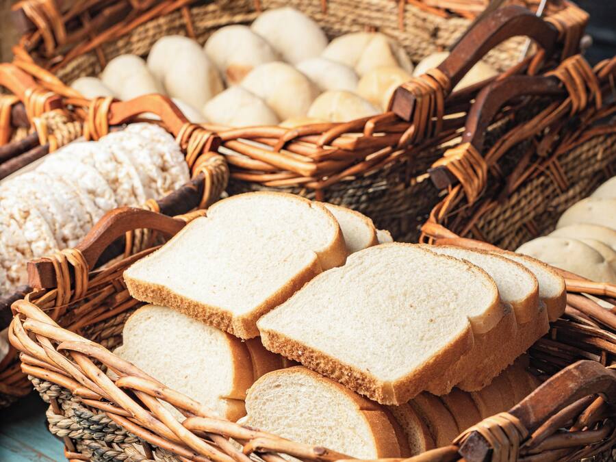 Wicker baskets filled with bread and eggs on a wooden surface.