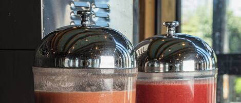 Two beverage dispensers with labels, placed on a counter with a window in the background.