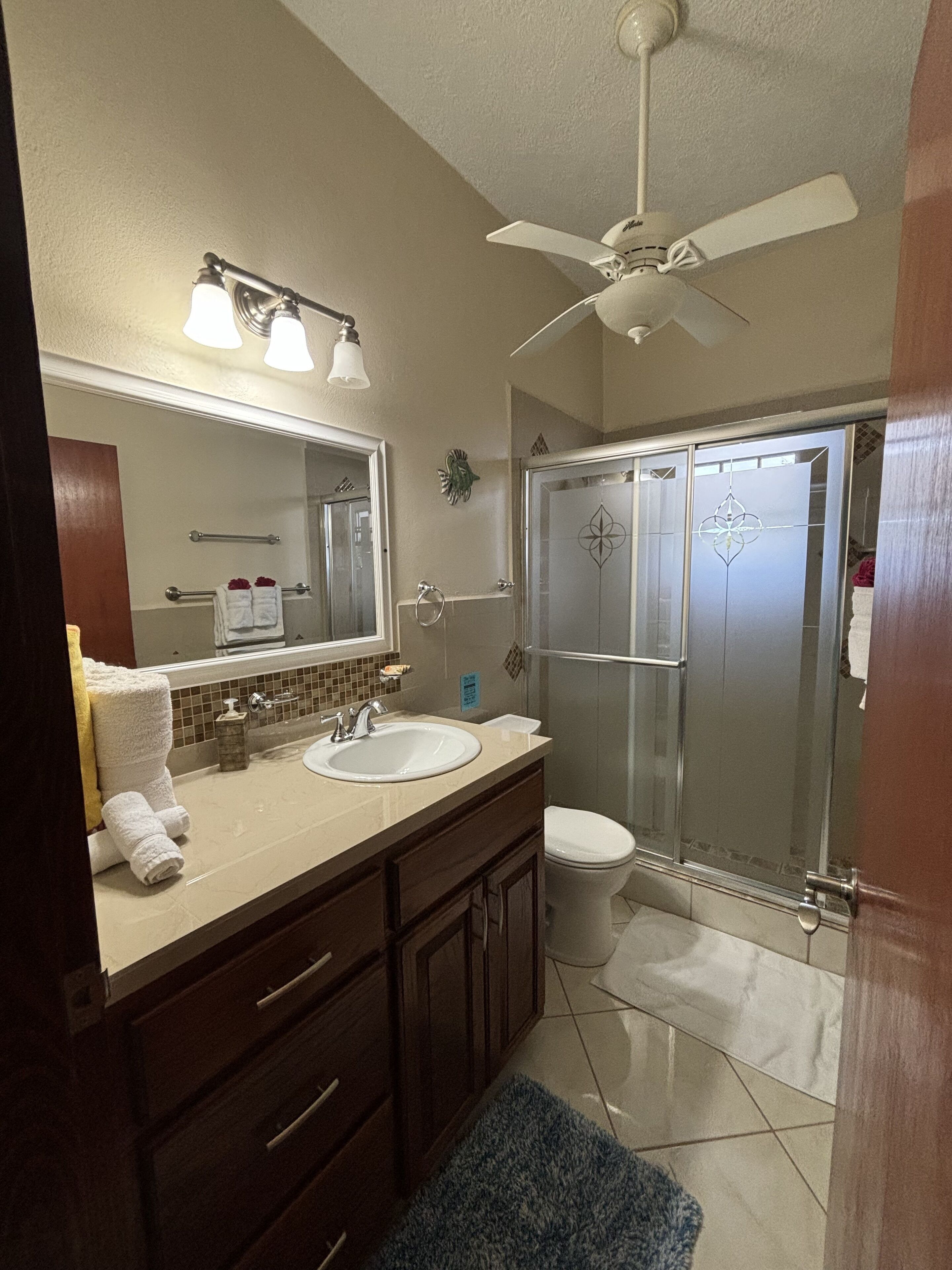 A bathroom with a sink, mirror, towel rack, and a shower enclosure.