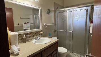 A bathroom with a sink, mirror, towel rack, and a shower enclosure.