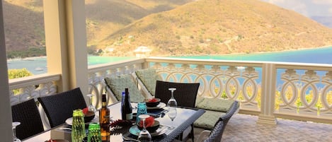 Mesa dispuesta para comer con vistas al mar y a las colinas.