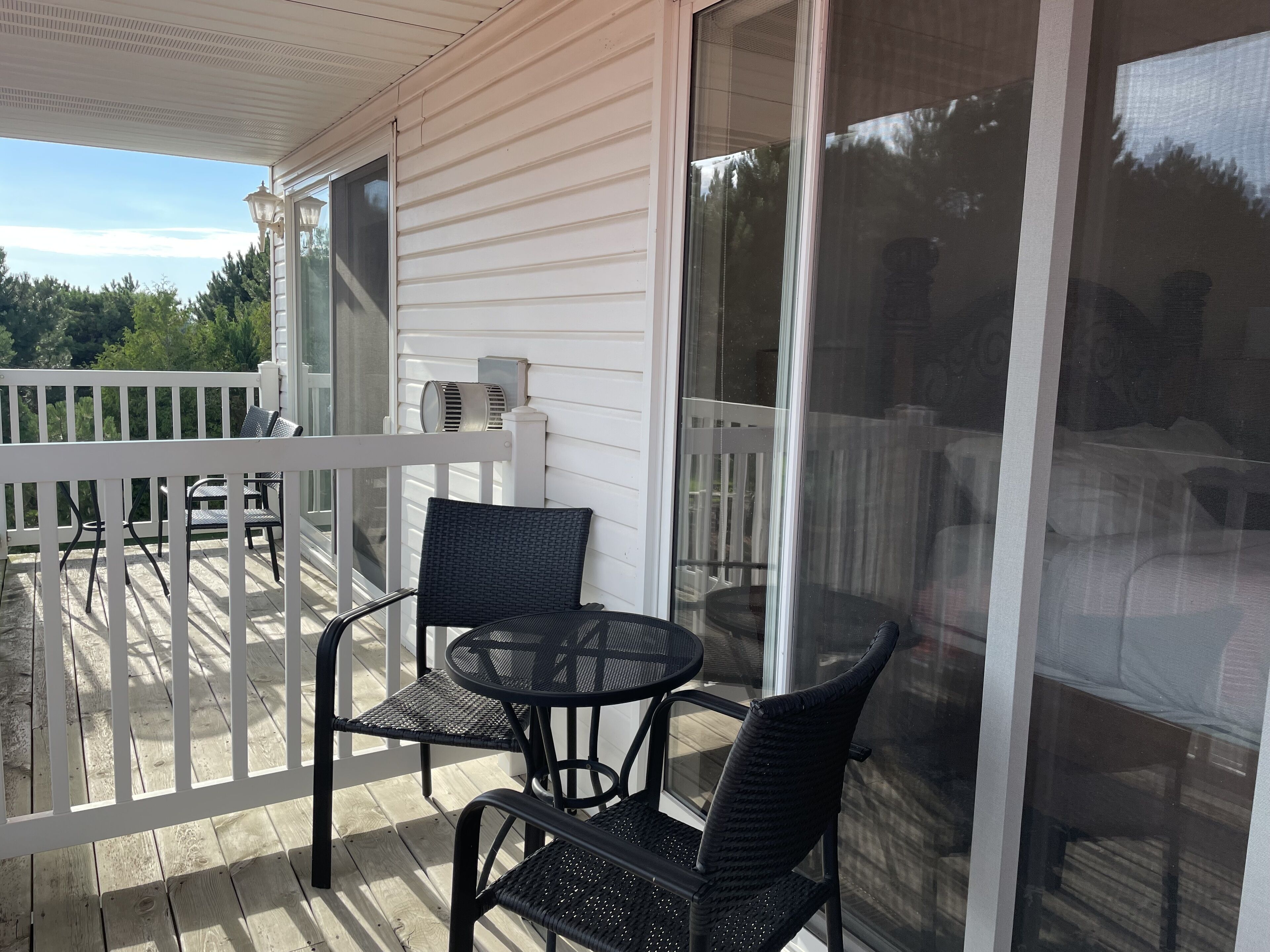 A covered outdoor area with a white railing, a table, and two chairs.