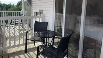 A covered outdoor area with a white railing, a table, and two chairs.