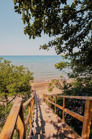 A wooden pathway leading to a beach with a wooden railing and a clear view of the sea. - Hessenland Inn & Schatz Winery (Bluewater)