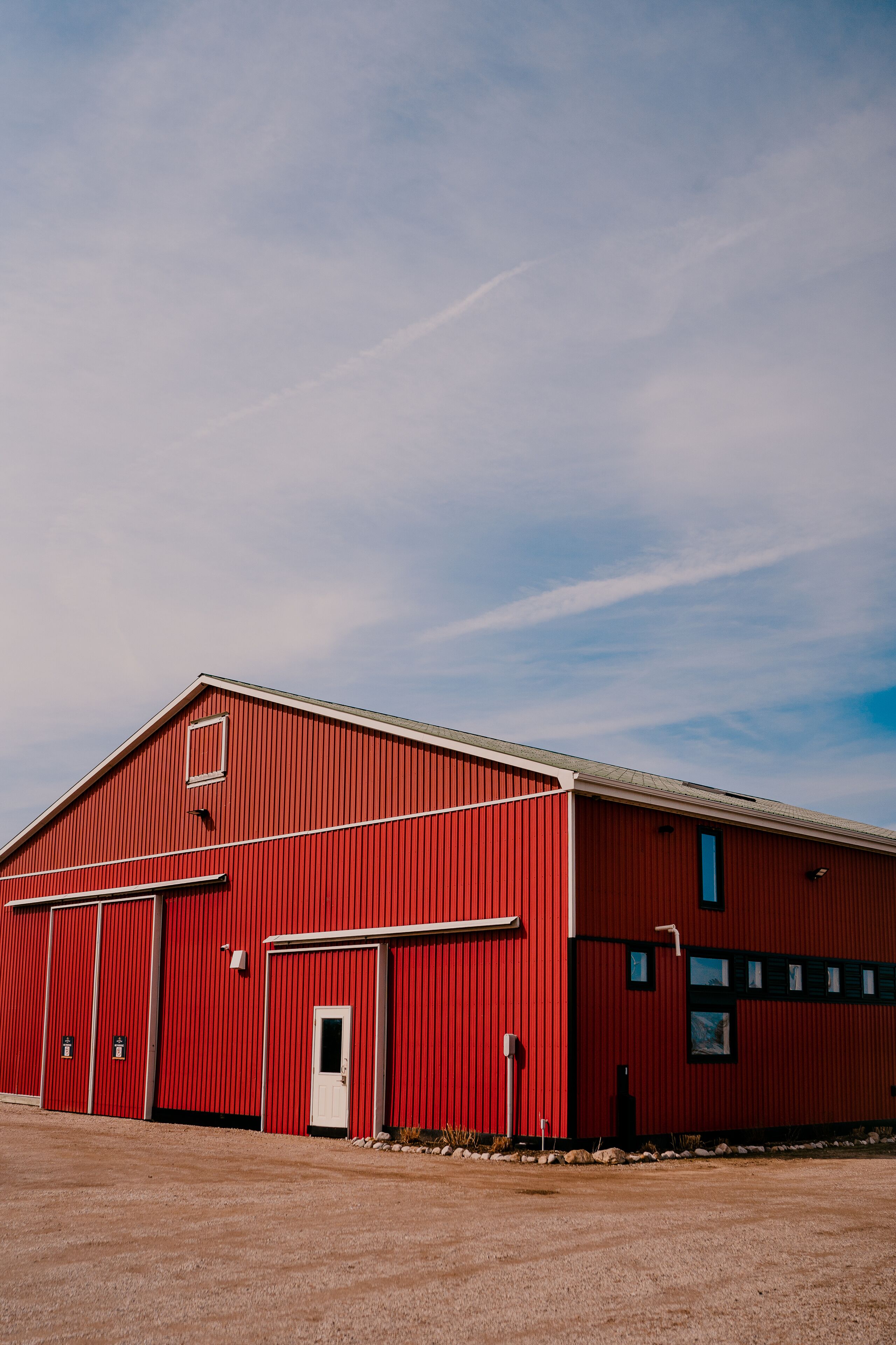 Un edificio industrial rojo con una puerta y ventanas, sobre un cielo despejado.