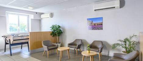 A modern lobby with a foosball table, comfortable seating, and a large window.
