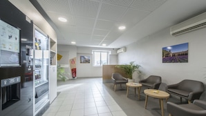 A modern waiting area with a vending machine, seating, and a large window. - B&B HOTEL Orange (Orange)