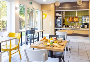 Un espace réservé au petit-déjeuner, avec des tables, des chaises et un comptoir où sont disposés les aliments.