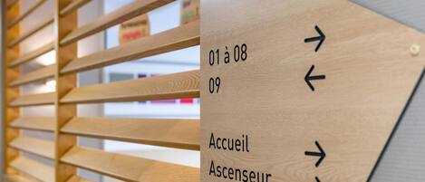 A directional sign with arrows pointing to different times and a label 'Accueil Ascenseur'.