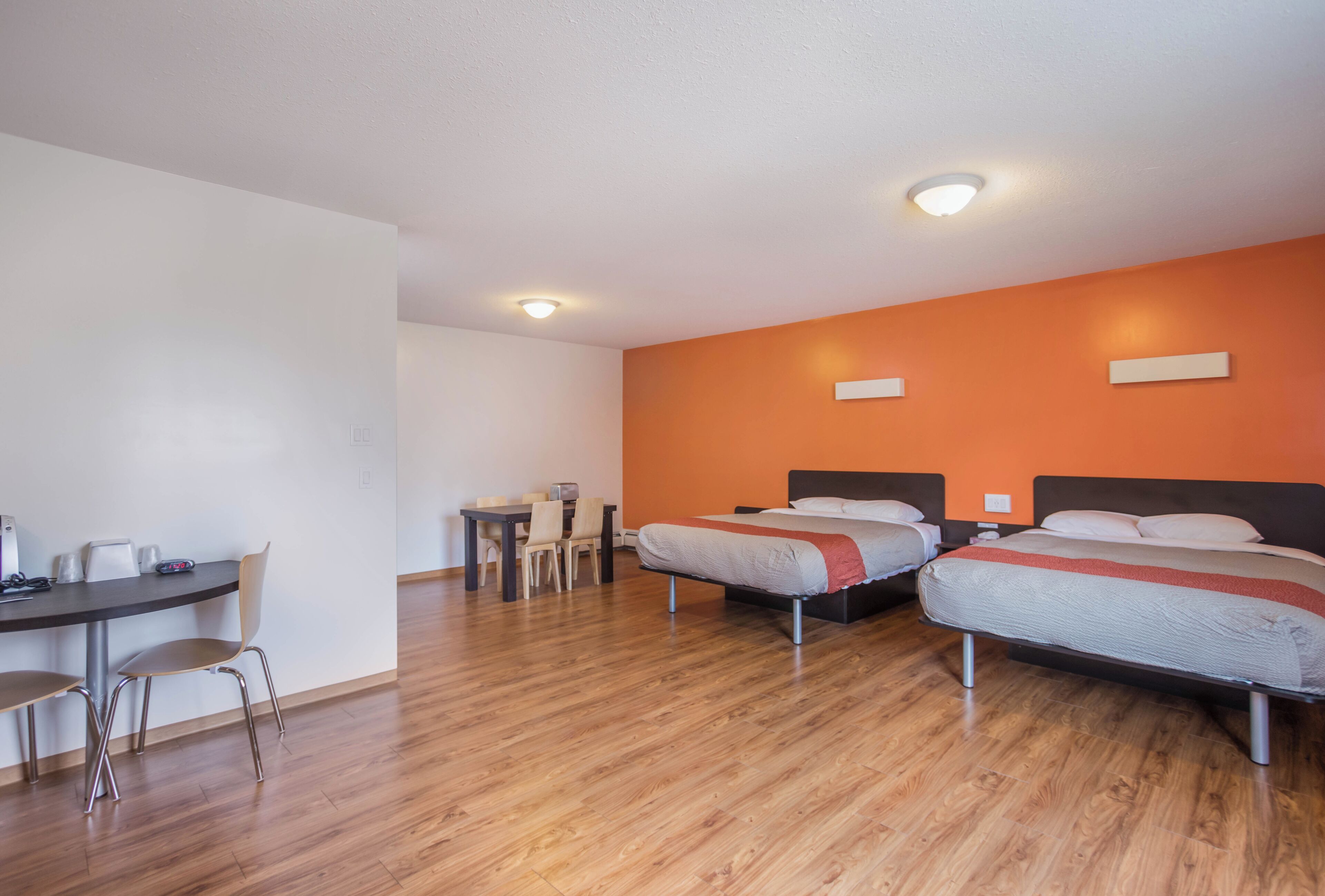 A hotel room with two beds, a desk, and a dining area.