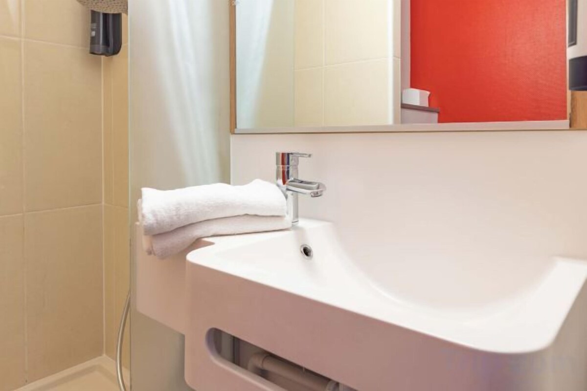 A bathroom with a white sink, a towel, and a mirror.