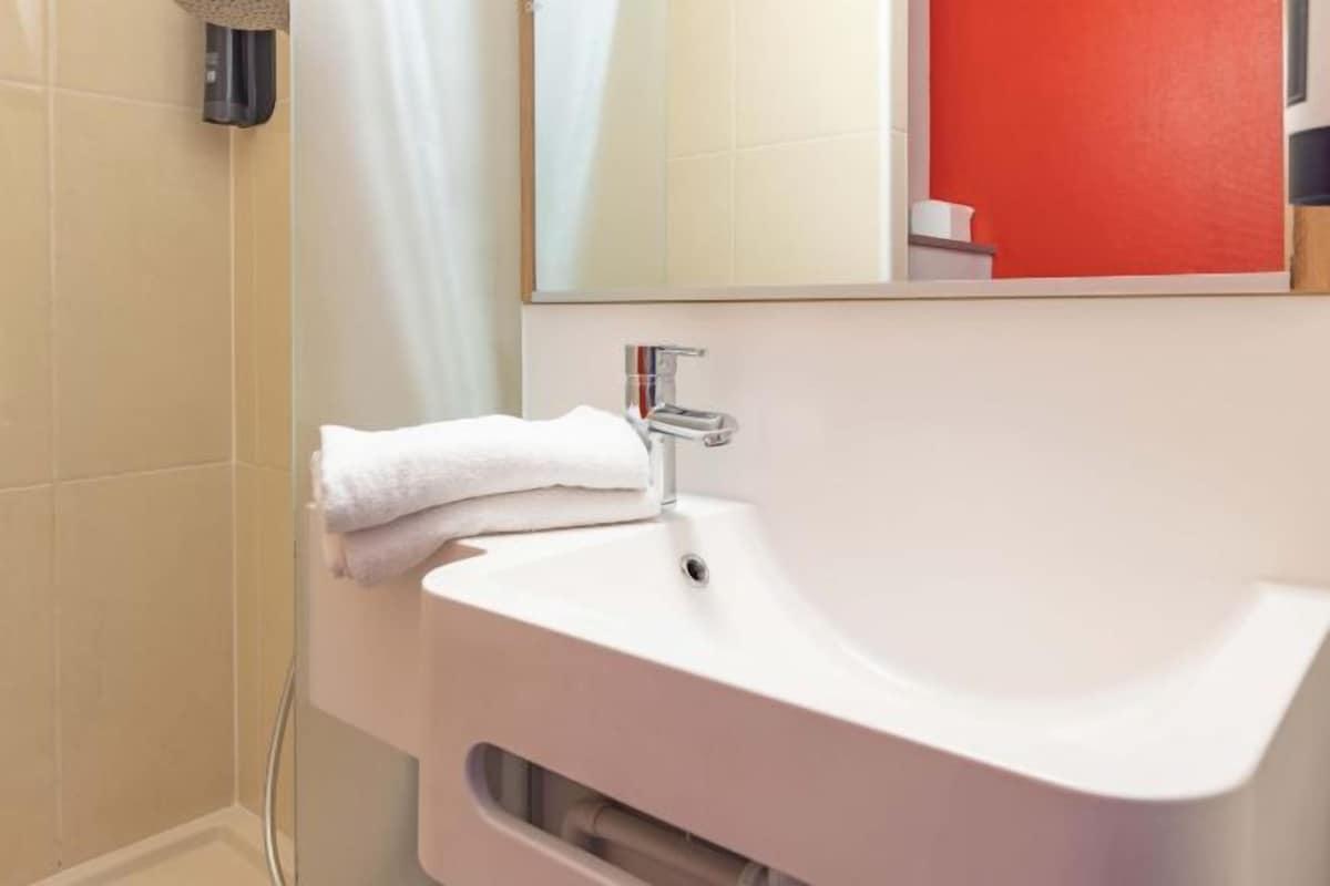 A bathroom with a white sink, a towel, and a mirror.