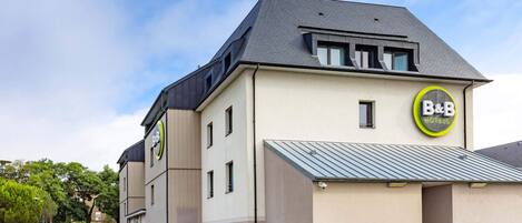 A B&B hotel with a modern design, featuring a two-story structure, a parking area, and a well-maintained garden.