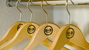 Perchas de madera con un logotipo en una barra metálica.