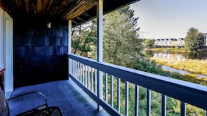 A covered porch with a view of a lake and buildings in the background.