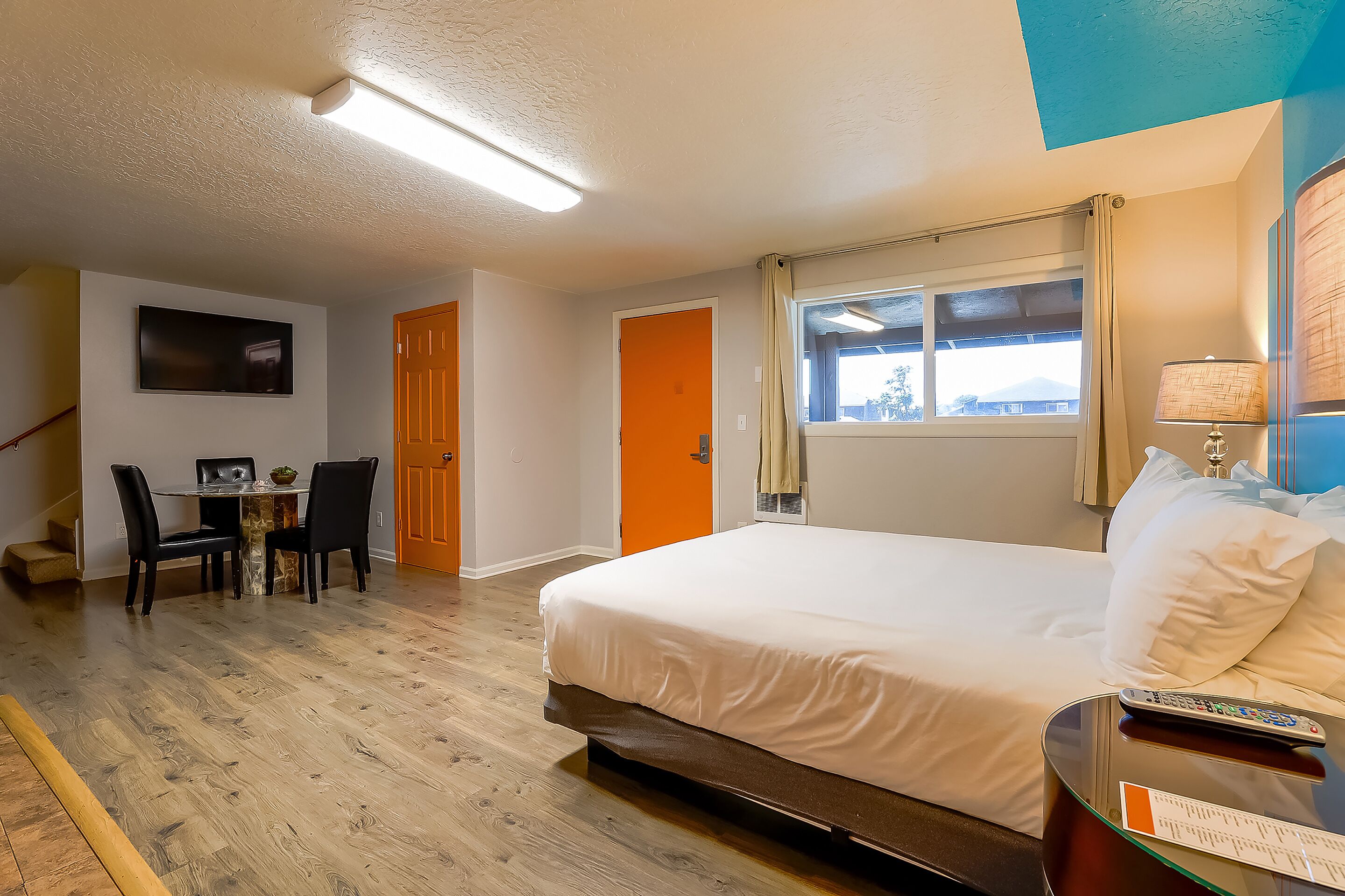 Une chambre d’hôtel comprenant un lit, un bureau avec une chaise, une télévision et une fenêtre avec des rideaux.