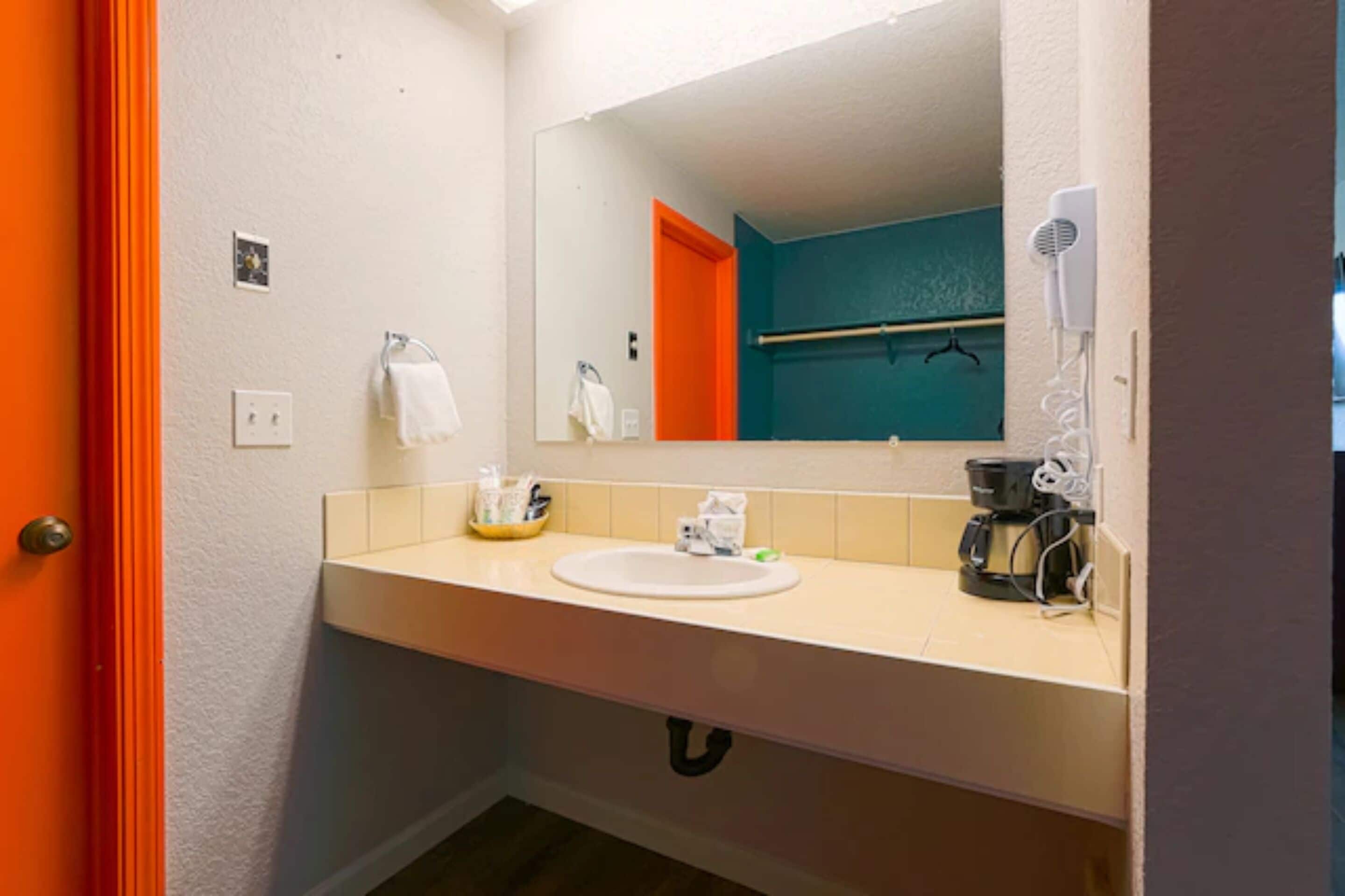 Une salle de bain équipée d’un lavabo, d’un miroir, d’un porte-serviettes et d’un sèche-cheveux.