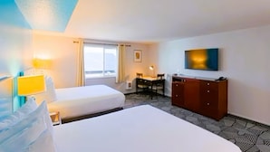 A hotel room with two beds, a desk, a chair, a wardrobe, and a TV on the wall.