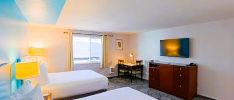 A hotel room with two beds, a desk, a chair, a wardrobe, and a TV on the wall.