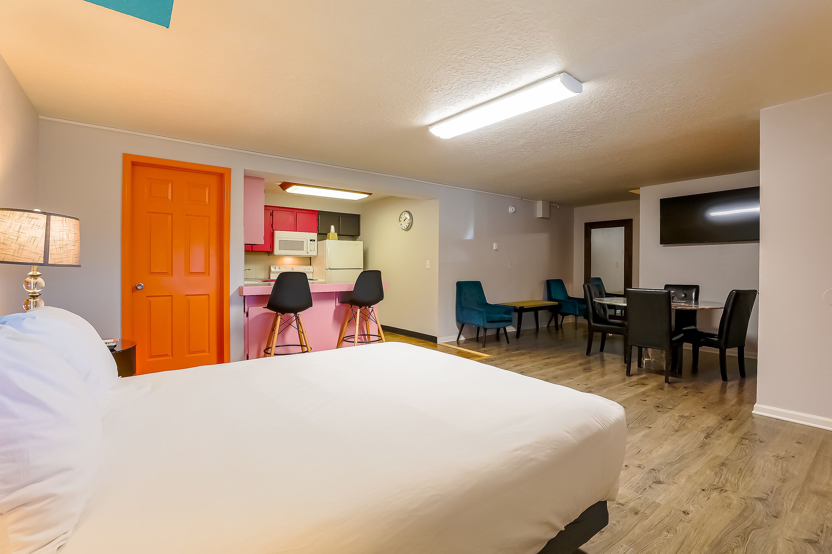Habitació d'hotel amb llit, escriptori amb cadires, zona de cuina i menjador.