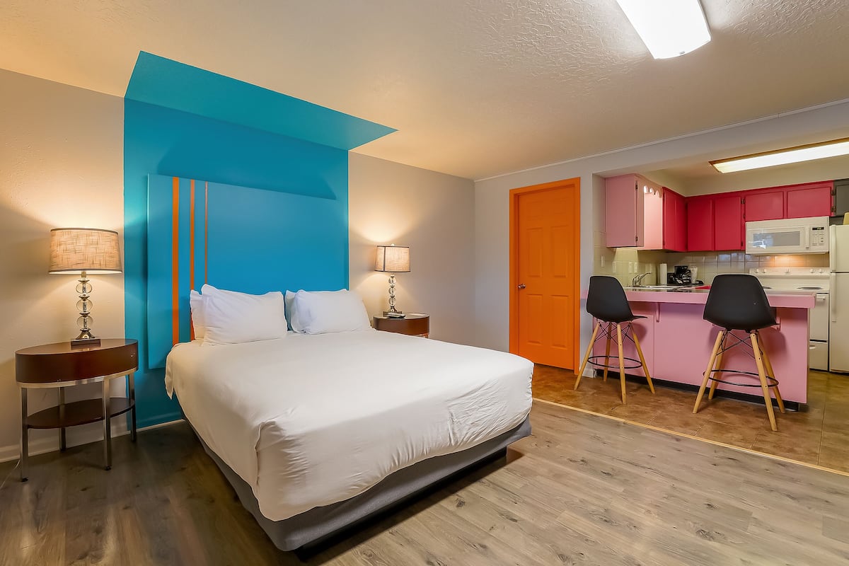 A bedroom with a bed, bedside tables, a nightstand, and a bathroom with a toilet and sink.