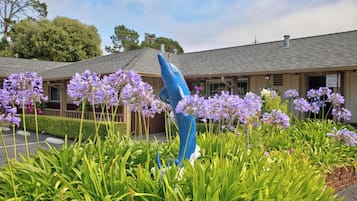 A building with a blue dolphin sculpture surrounded by purple flowers.