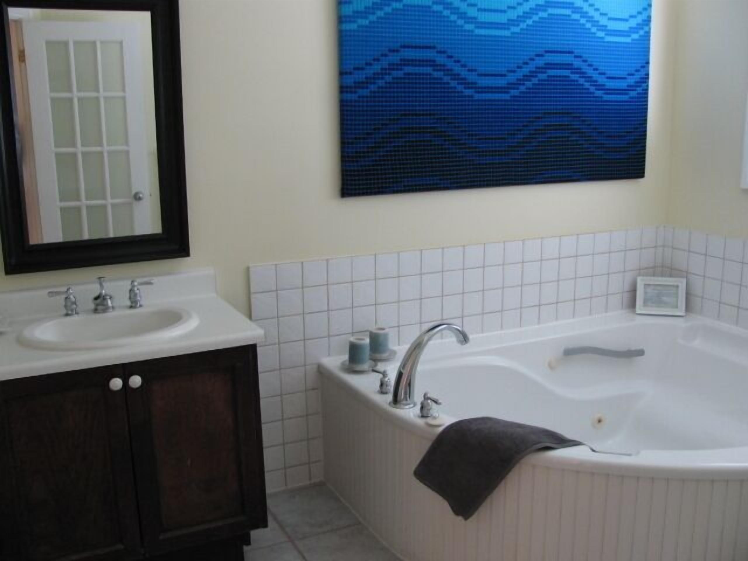 Une salle de bain dotée d’un meuble-lavabo à deux vasques, d’une grande baignoire et d’un miroir fixé au mur.