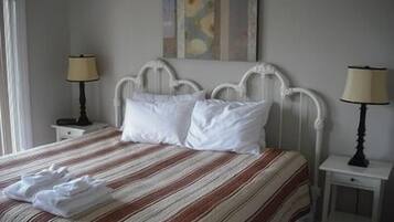 A bed with a striped bedspread, two white pillows, and a folded towel. There are two bedside tables with lamps.