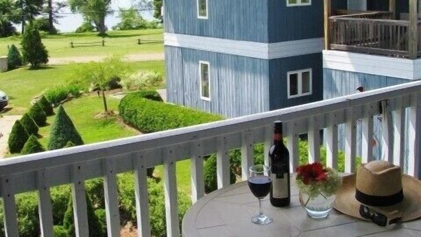 Ein blaues Gebäude mit einem Balkon, einem Tisch mit einer Weinflasche und einem Hut.
