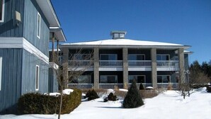 Ein zweistöckiges Gebäude mit schneebedecktem Dach und einem Balkon im zweiten Stock.