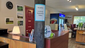 Ein Empfangsschalter mit einem Schild für Calabogie Highlands Villas, einer Uhr und gerahmten Bildern an der Wand.