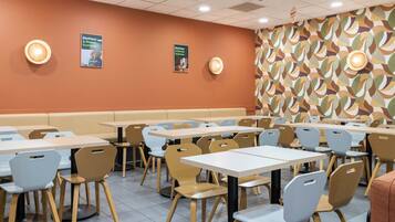 Un restaurante con varias mesas y sillas, un muro con diseño y dos carteles en la pared.