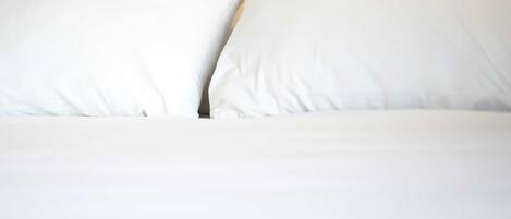 A bed with white bedding and pillows.