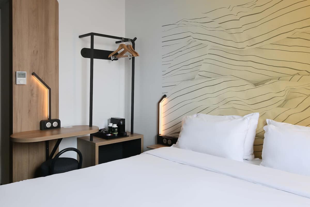 Habitación de hotel con cama, mesitas de noche, perchero en la pared y diseño de pared con textura.