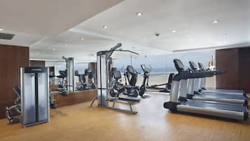 Et moderne fitnesscenter med løbebånd, styrkemaskiner og havudsigt.
