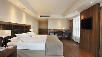A hotel room with a large bed, a desk, a TV, and a bathroom visible through an open door.