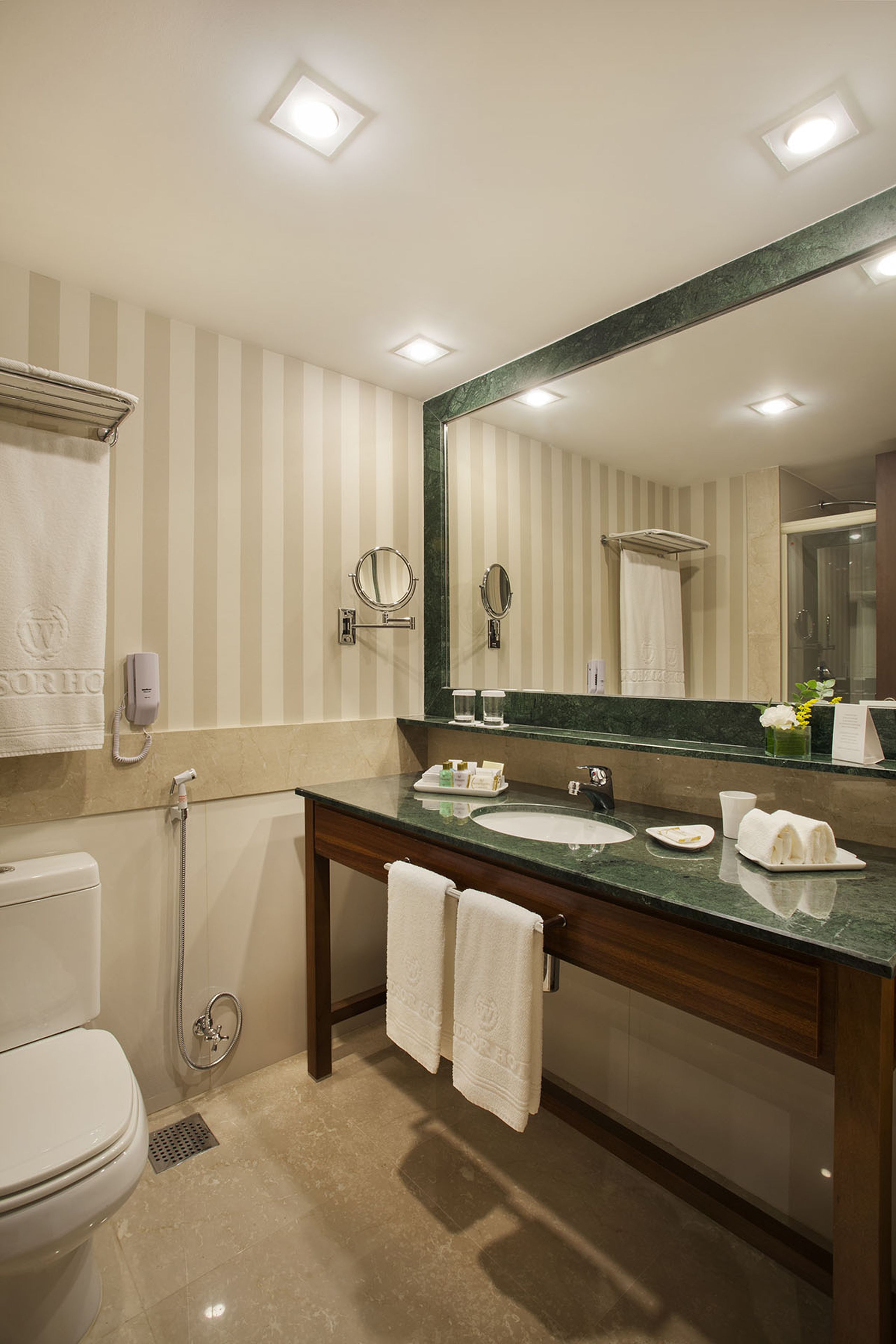 Un baño moderno con un espejo grande, dos lavamanos, un inodoro y una ducha.