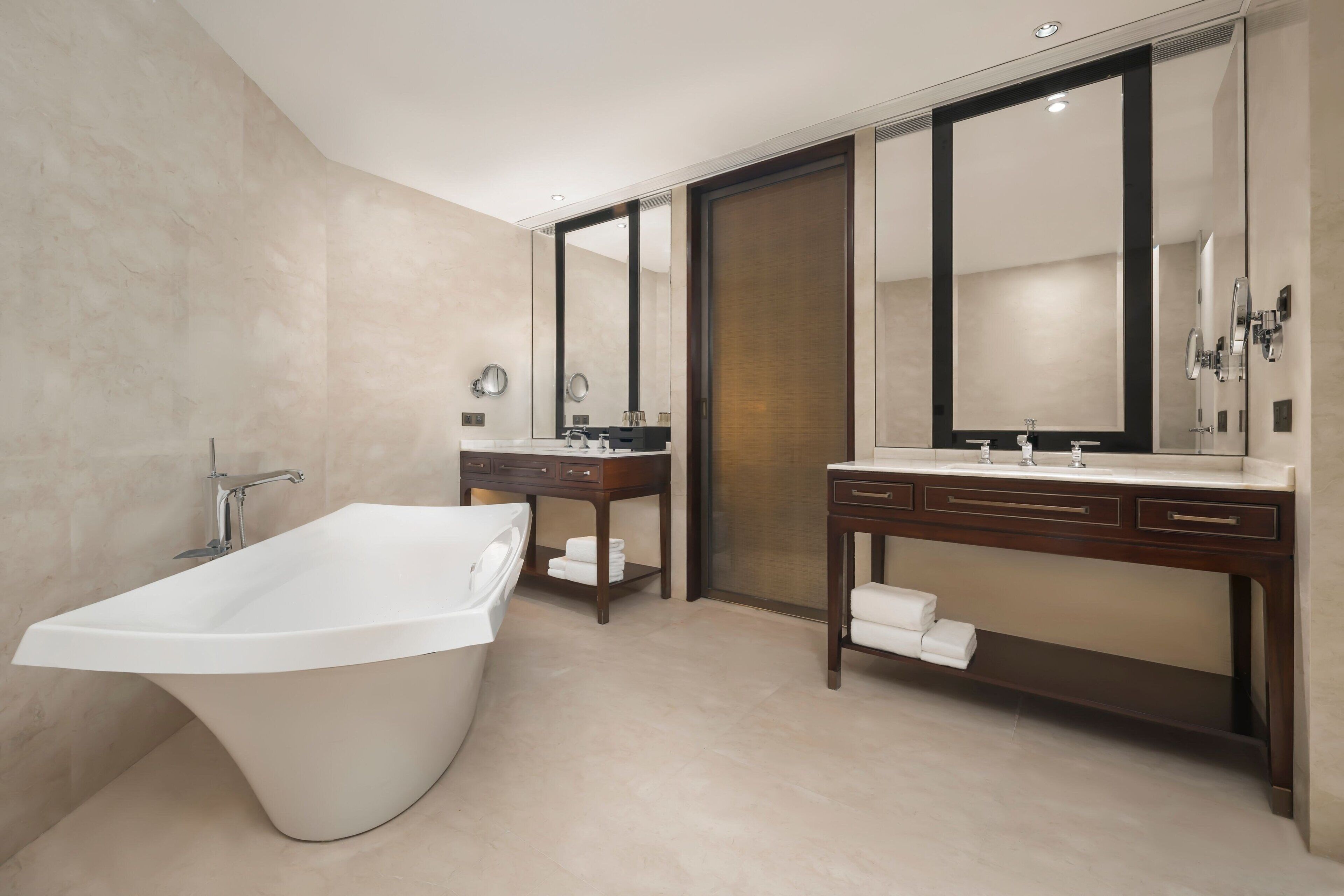 A modern bathroom with a freestanding bathtub, a vanity with a mirror, and a large mirror above the vanity.