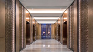 A modern hotel corridor with a reflective floor, decorative panels, and a blue door at the end. - Sheraton Shanghai Jiading Hotel (Shanghai)